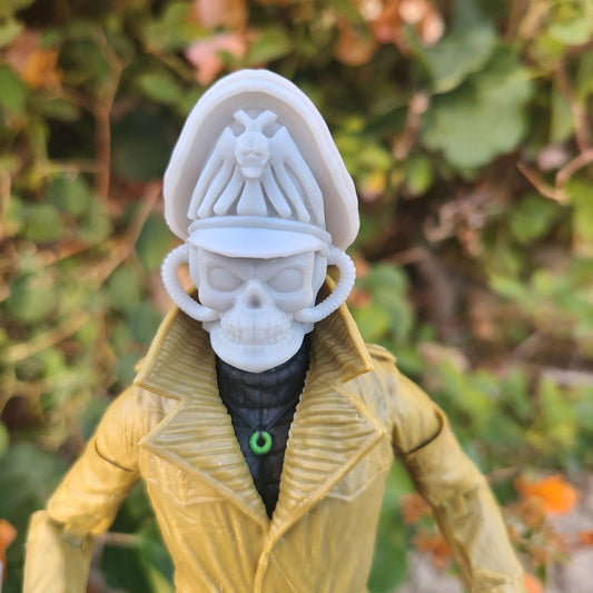 A 1/12 scale action figure head swap, featuring a skull with hoses and a commissar hat. The figure is painted in white and gray tones, with red details on the hat.